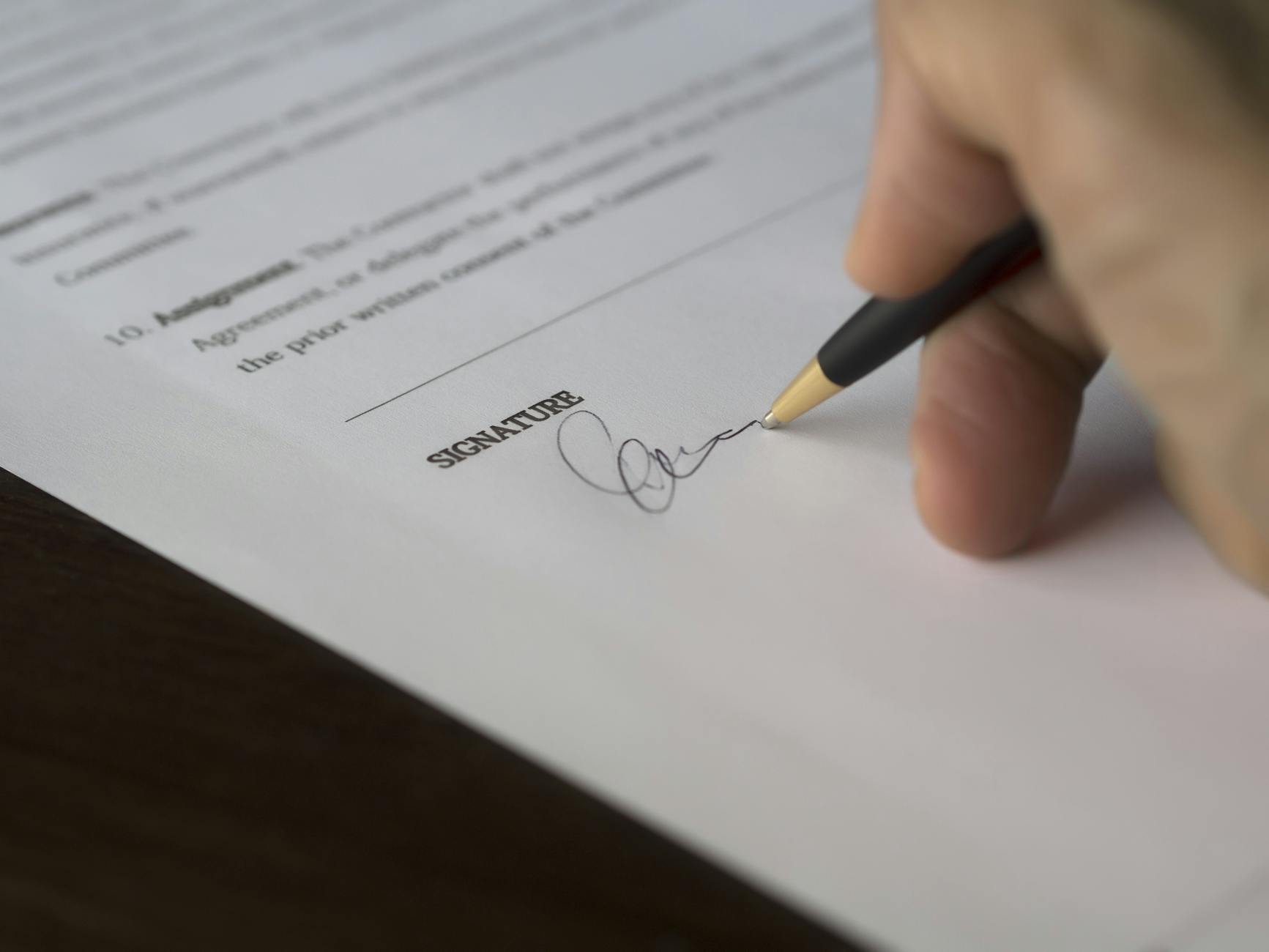 selective focus photography of person signing on paper